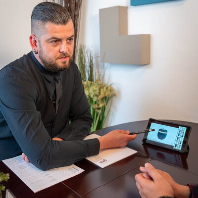 Mitarbeiter vom Bestattungsinstitut Gann in Weil der Stadt zeigt einem Besucher Urnenmodelle auf einem Tablet