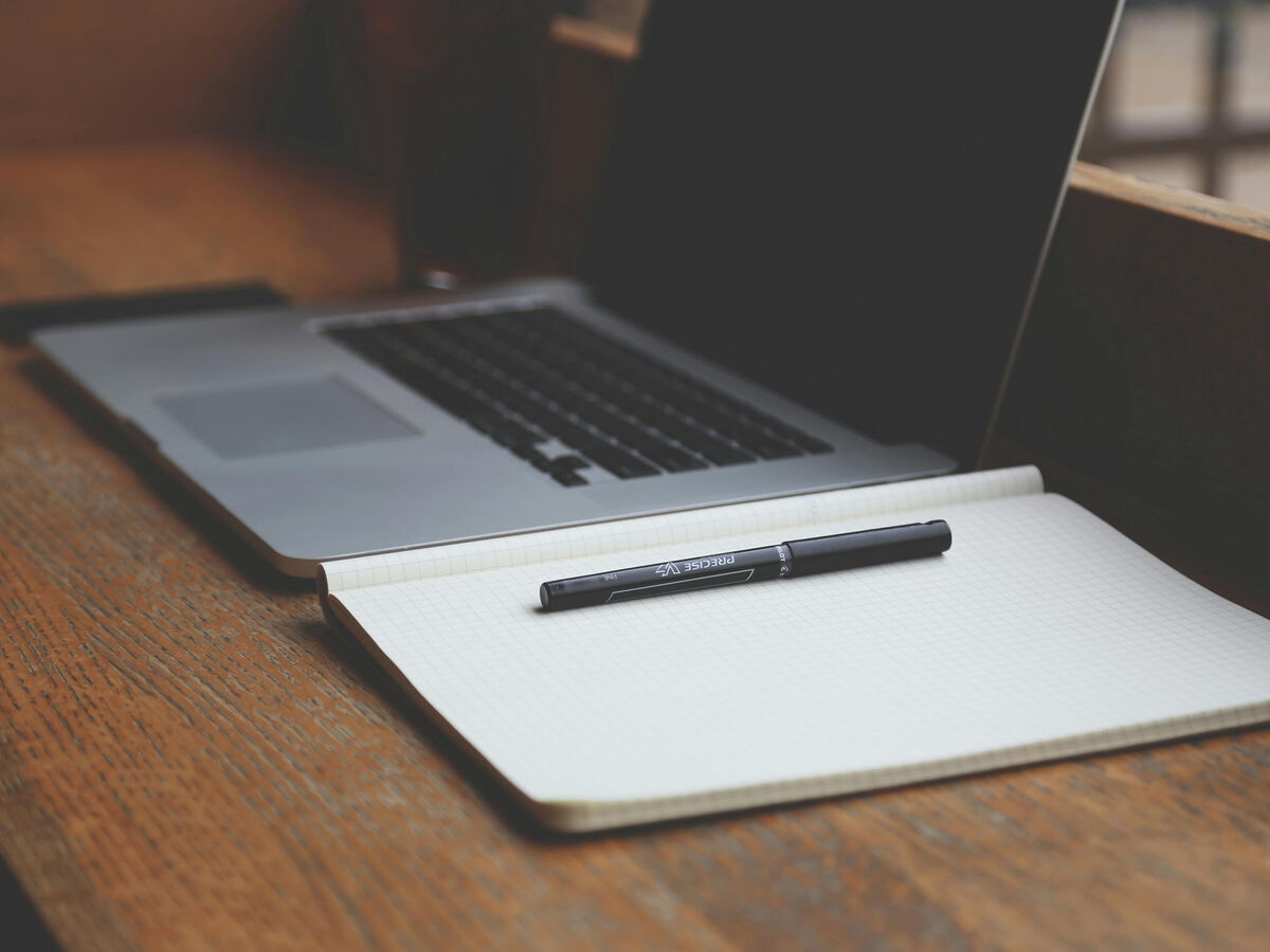 Laptop und Notizbuch mit Stift